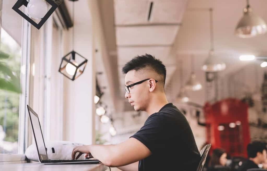 Asian man works on laptop